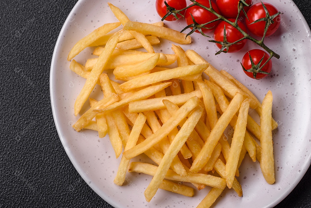 Deliciosas fatias de batata frita crocante com sal, especiarias e ervas sobre um fundo escuro de concreto