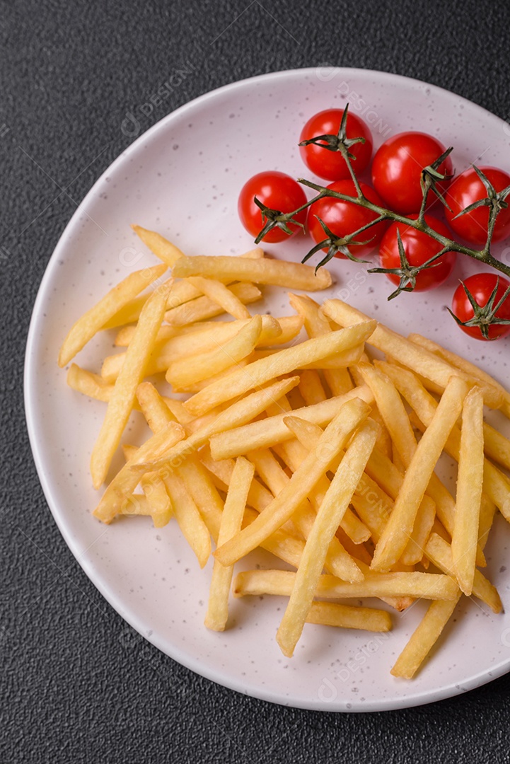 Frescas e deliciosas batatas fritas crocantes com sal e especiarias sobre um fundo escuro de concreto