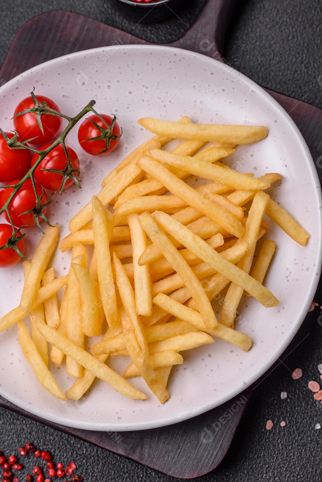 Frescas e deliciosas batatas fritas crocantes com sal e especiarias sobre um fundo escuro de concreto