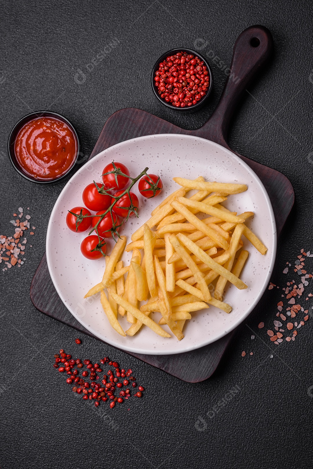 Frescas e deliciosas batatas fritas crocantes com sal e especiarias sobre um fundo escuro de concreto