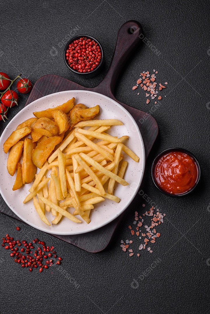 Frescas e deliciosas batatas fritas crocantes com sal e especiarias sobre um fundo escuro de concreto