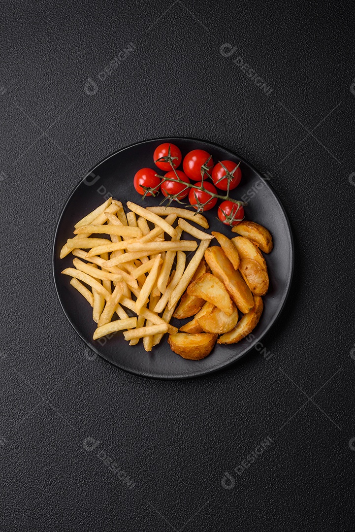 Deliciosas fatias de batata frita crocante com sal, especiarias e ervas sobre um fundo escuro de concreto