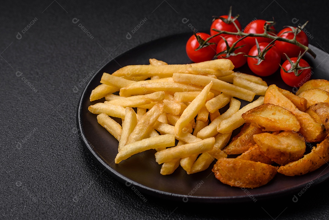 Deliciosas fatias de batata frita crocante com sal, especiarias e ervas sobre um fundo escuro de concreto