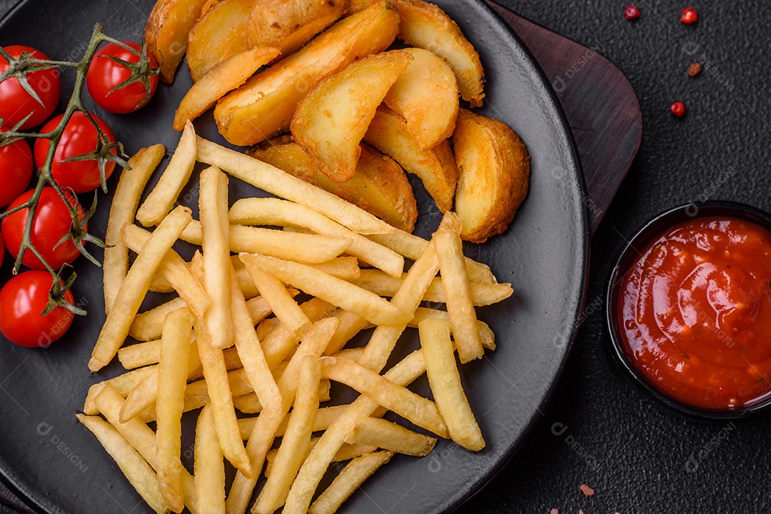 Deliciosas fatias de batata frita crocante com sal, especiarias e ervas sobre um fundo escuro de concreto