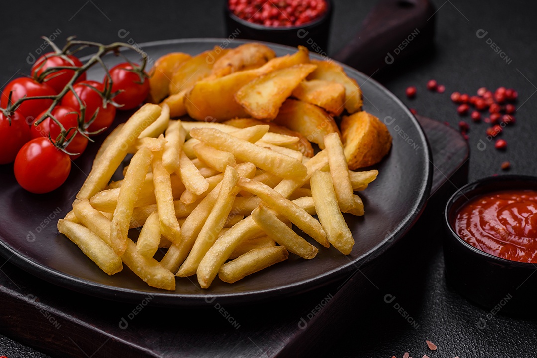 Deliciosas fatias de batata frita crocante com sal, especiarias e ervas sobre um fundo escuro de concreto