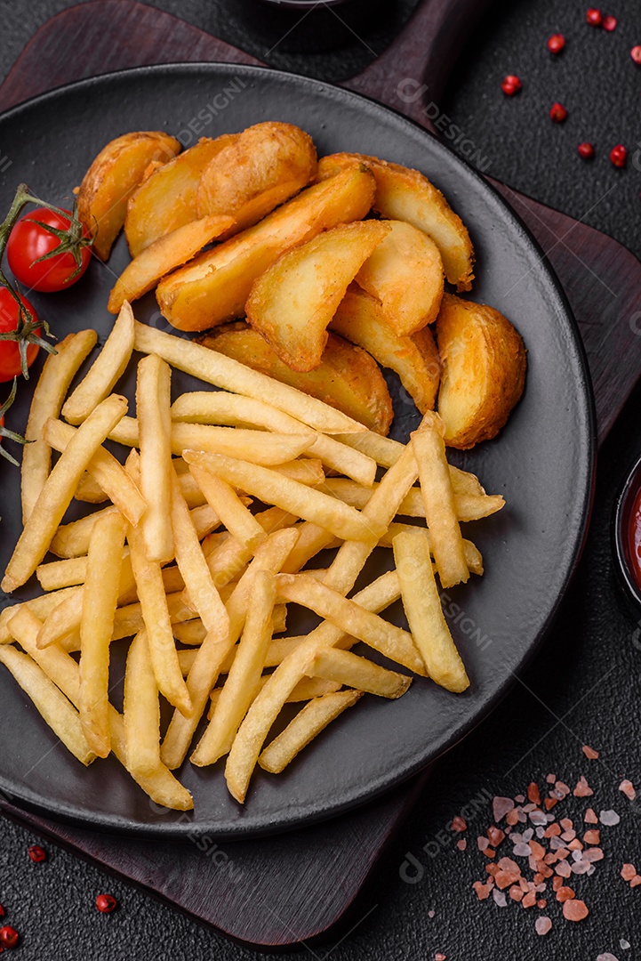 Deliciosas fatias de batata frita crocante com sal, especiarias e ervas sobre um fundo escuro de concreto