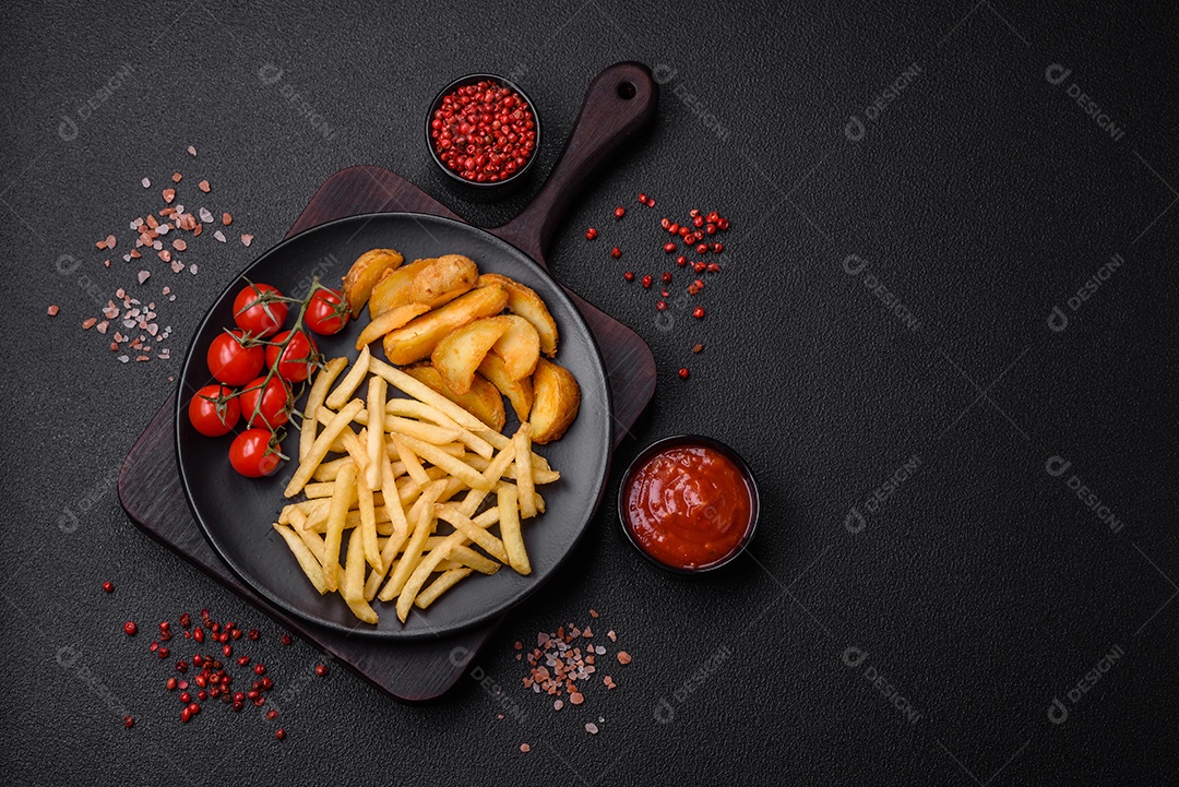 Deliciosas fatias de batata frita crocante com sal, especiarias e ervas sobre um fundo escuro de concreto