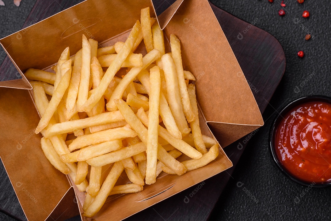 Deliciosas fatias de batata frita crocante com sal, especiarias e ervas sobre um fundo escuro de concreto