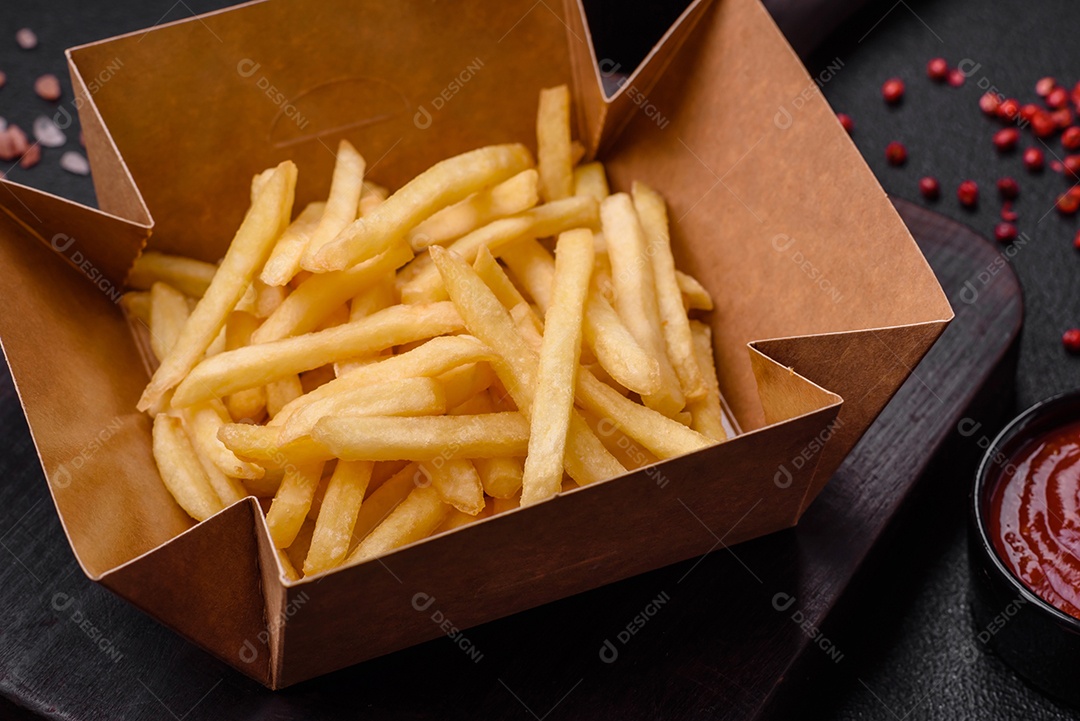 Deliciosas fatias de batata frita crocante com sal, especiarias e ervas sobre um fundo escuro de concreto