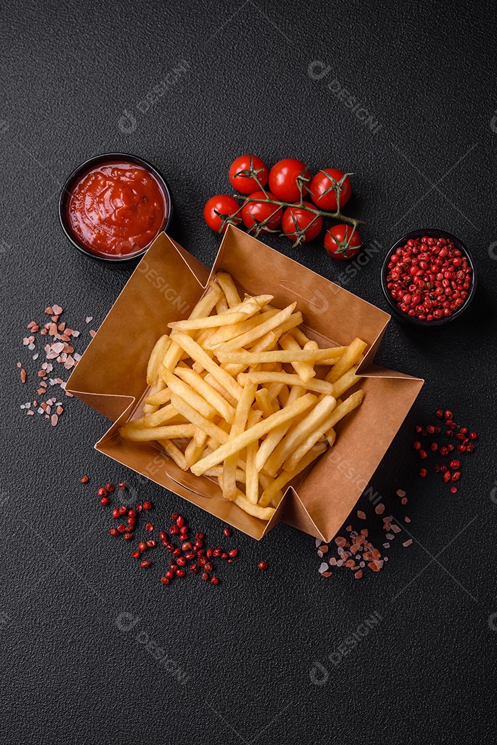 Deliciosas fatias de batata frita crocante com sal, especiarias e ervas sobre um fundo escuro de concreto