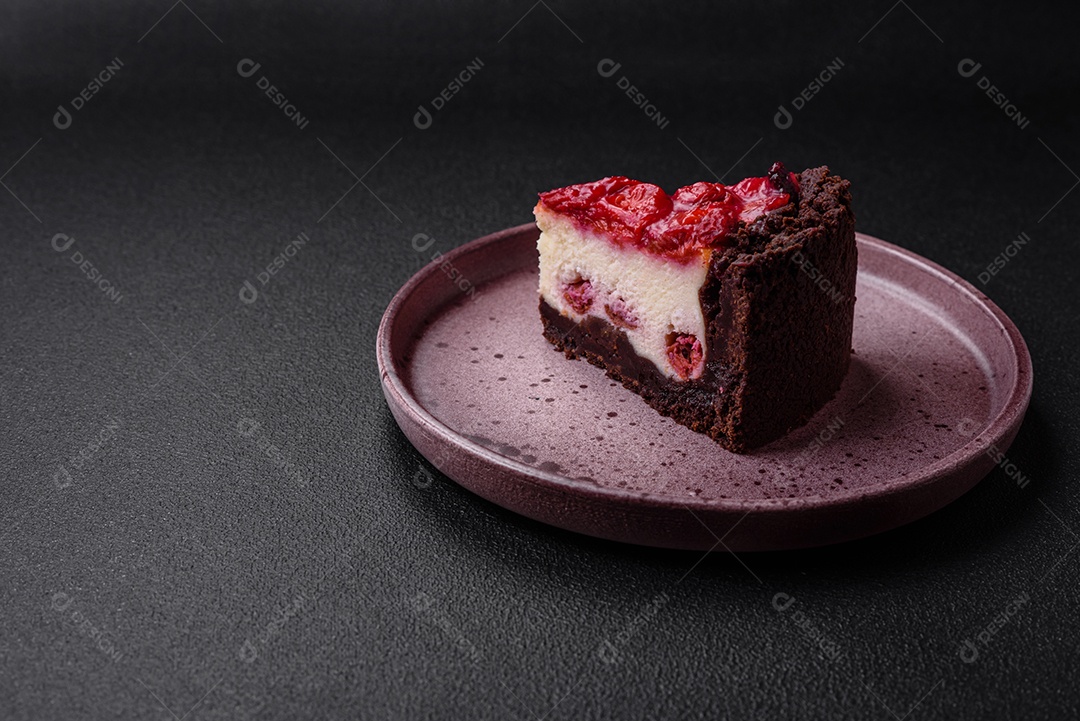 Linda e saborosa fatia doce de cheesecake com cereja em uma placa de cerâmica sobre um fundo escuro de concreto