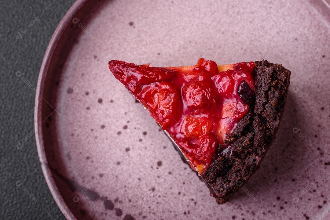Linda e saborosa fatia doce de cheesecake com cereja em uma placa de cerâmica sobre um fundo escuro de concreto