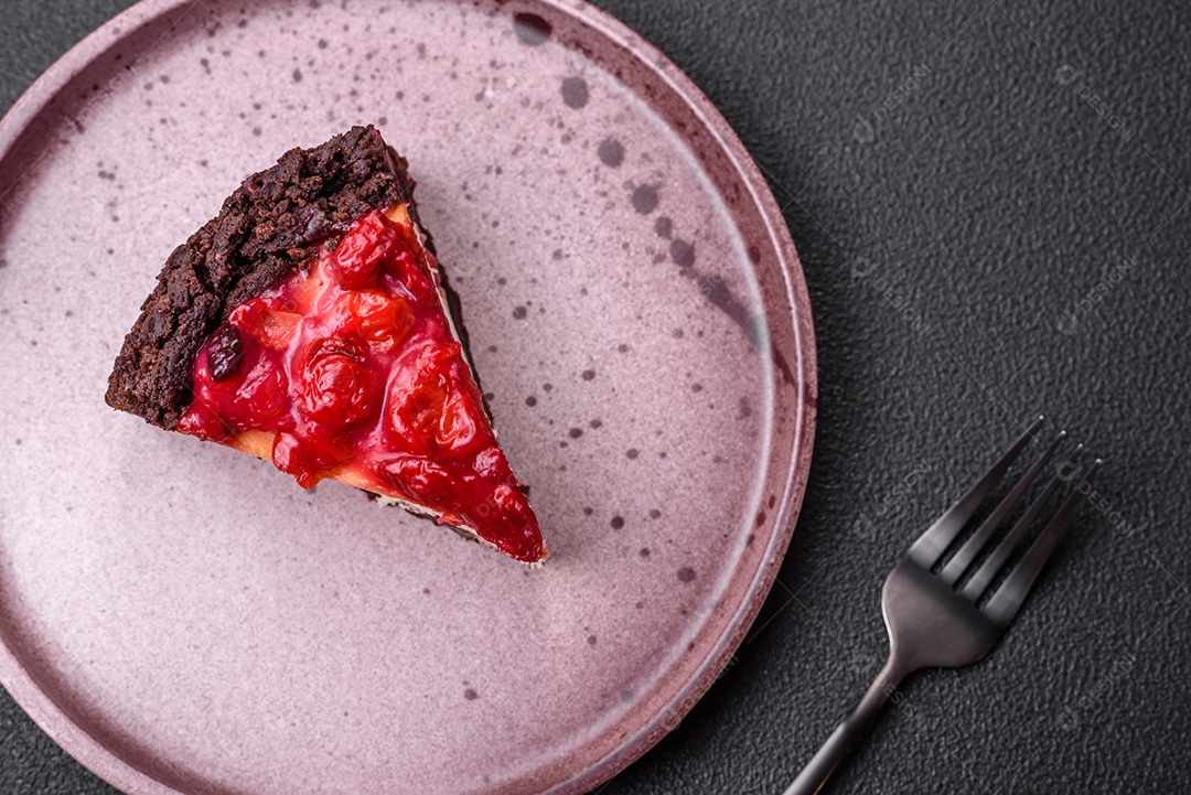 Linda e saborosa fatia doce de cheesecake com cereja em uma placa de cerâmica sobre um fundo escuro de concreto
