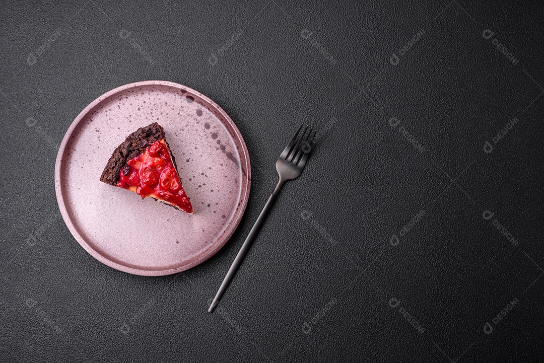 Linda e saborosa fatia doce de cheesecake com cereja em uma placa de cerâmica sobre um fundo escuro de concreto