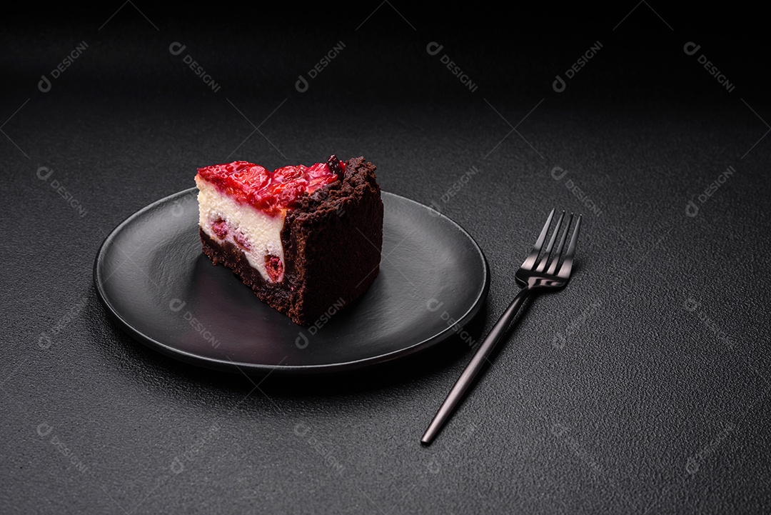 Linda e saborosa fatia doce de cheesecake com cereja em uma placa de cerâmica sobre um fundo escuro de concreto