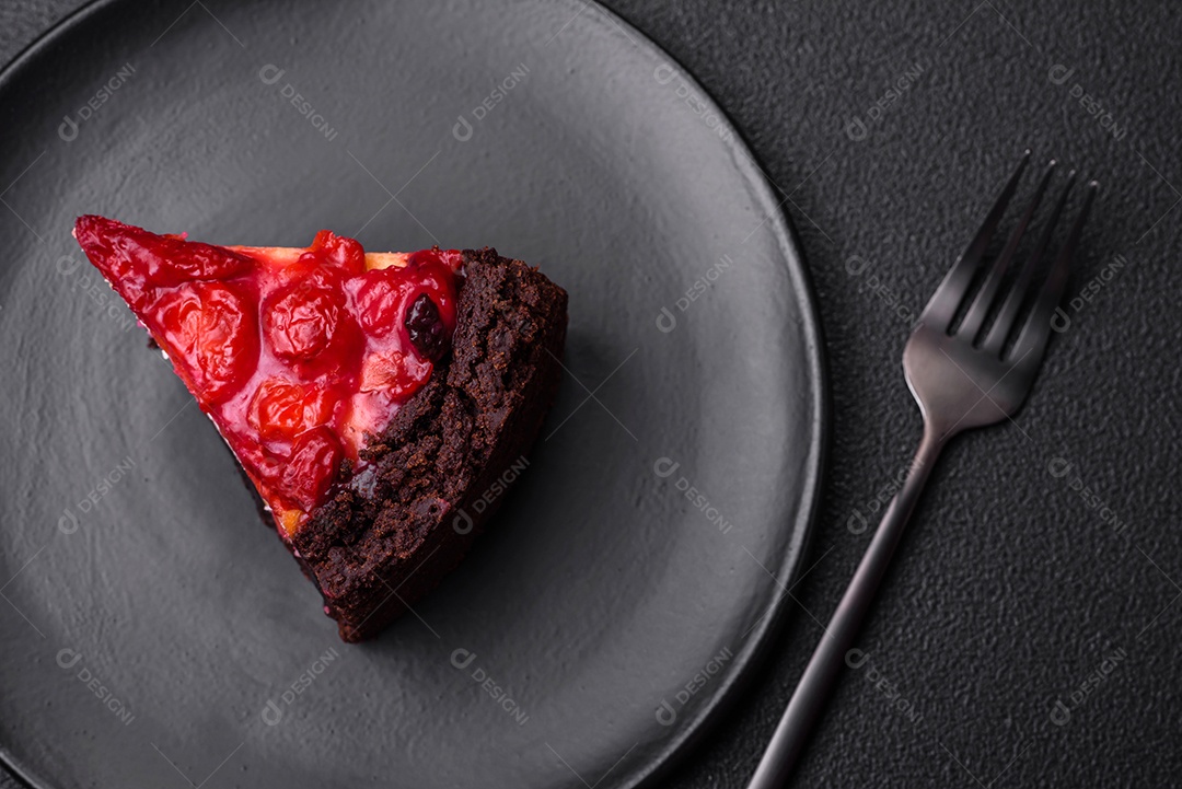 Linda e saborosa fatia doce de cheesecake com cereja em uma placa de cerâmica sobre um fundo escuro de concreto