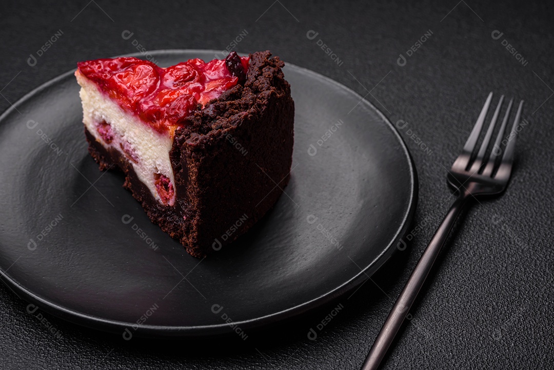 Linda e saborosa fatia doce de cheesecake com cereja em uma placa de cerâmica sobre um fundo escuro de concreto