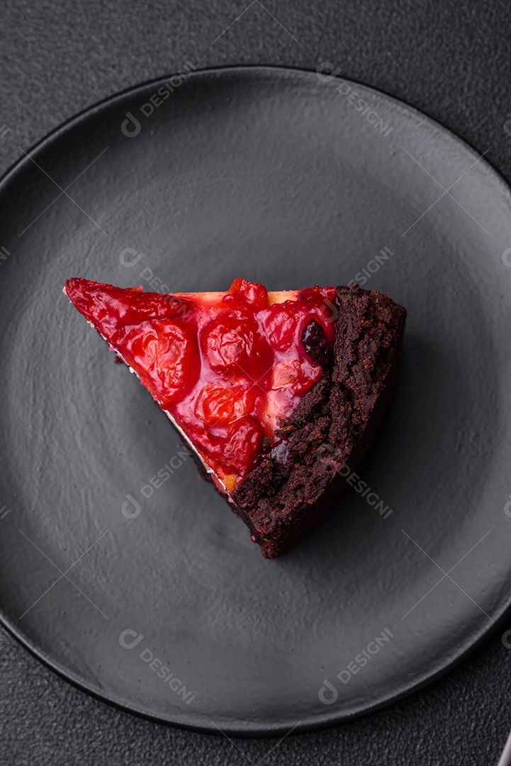 Linda e saborosa fatia doce de cheesecake com cereja em uma placa de cerâmica sobre um fundo escuro de concreto