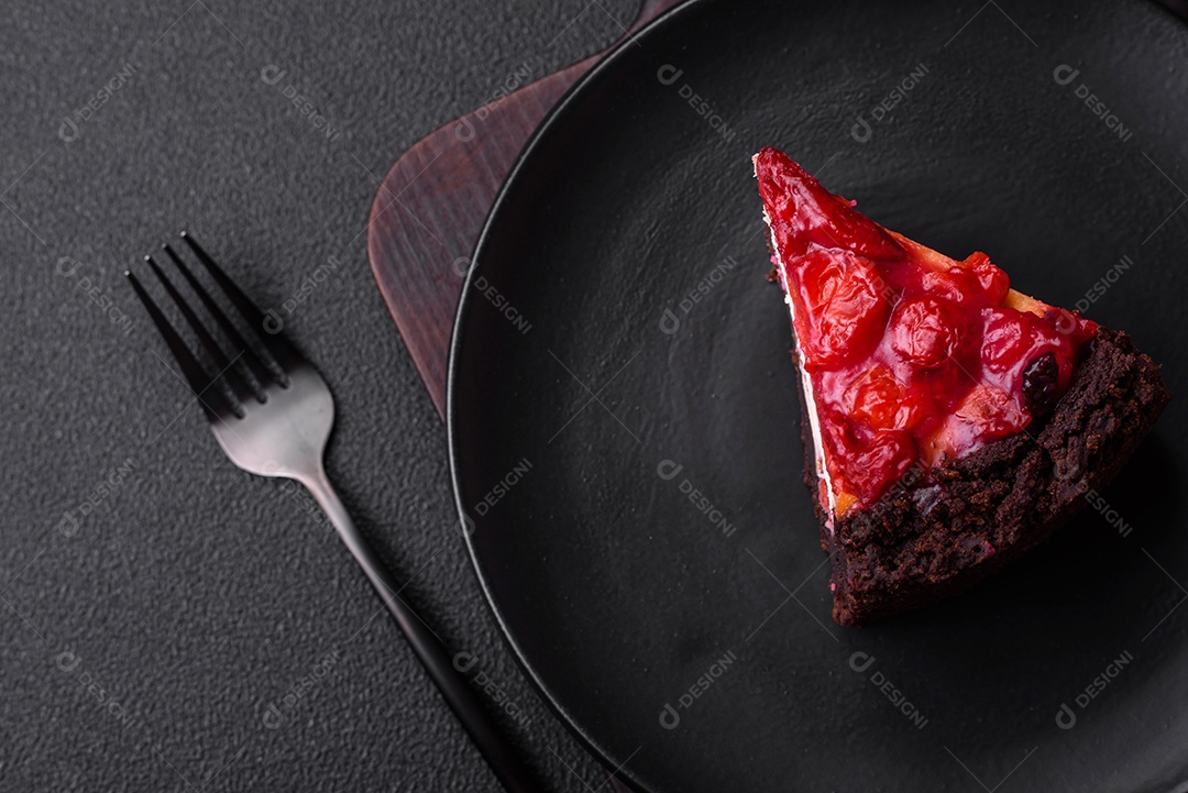 Linda e saborosa fatia doce de cheesecake com cereja em uma placa de cerâmica sobre um fundo escuro de concreto