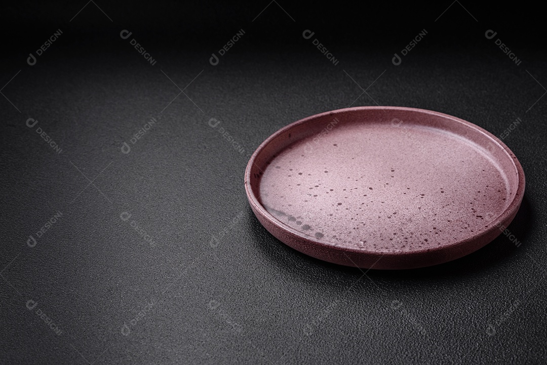 Prato cerâmico vazio em um fundo escuro texturizado. Preparando utensílios de cozinha para um jantar em família