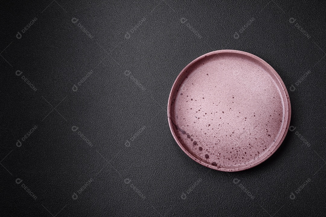 Prato cerâmico vazio em um fundo escuro texturizado. Preparando utensílios de cozinha para um jantar em família