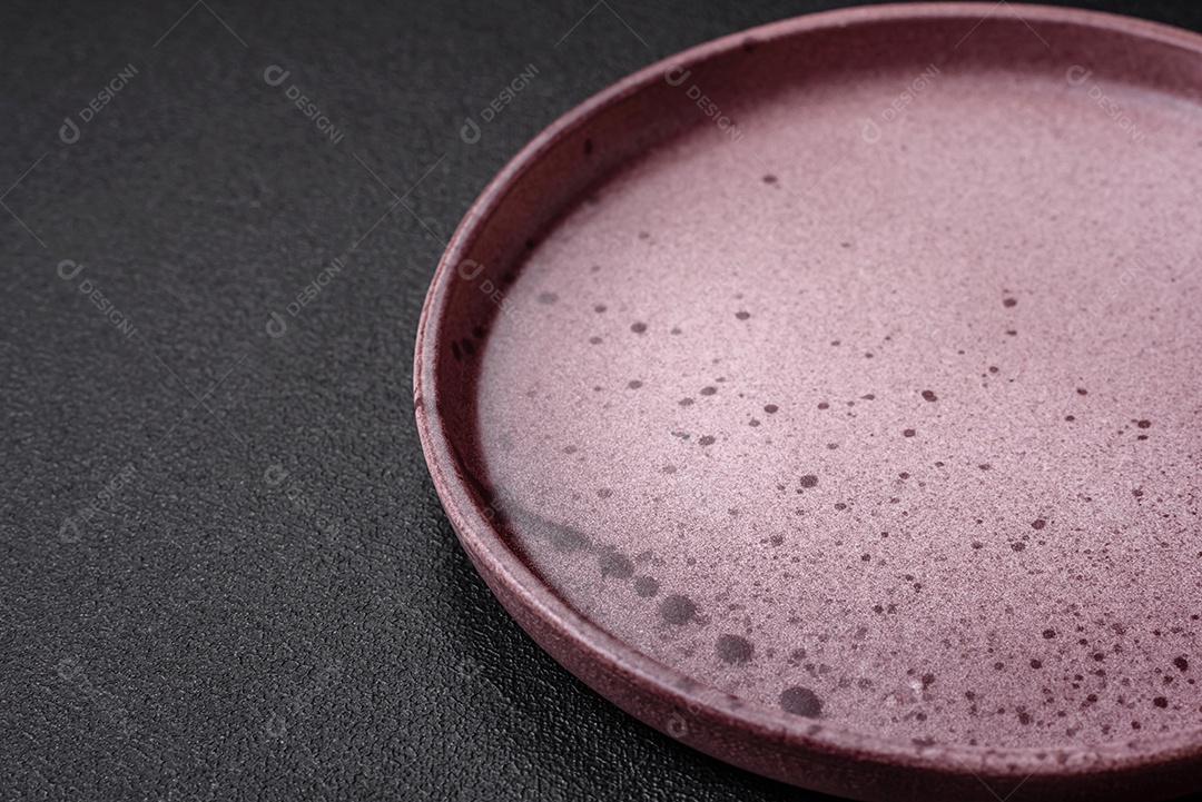 Prato cerâmico vazio em um fundo escuro texturizado. Preparando utensílios de cozinha para um jantar em família