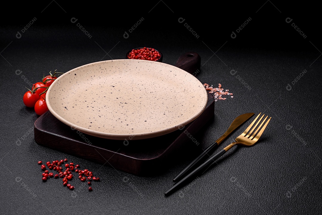 Prato cerâmico vazio em um fundo escuro texturizado. Preparando utensílios de cozinha para um jantar em família