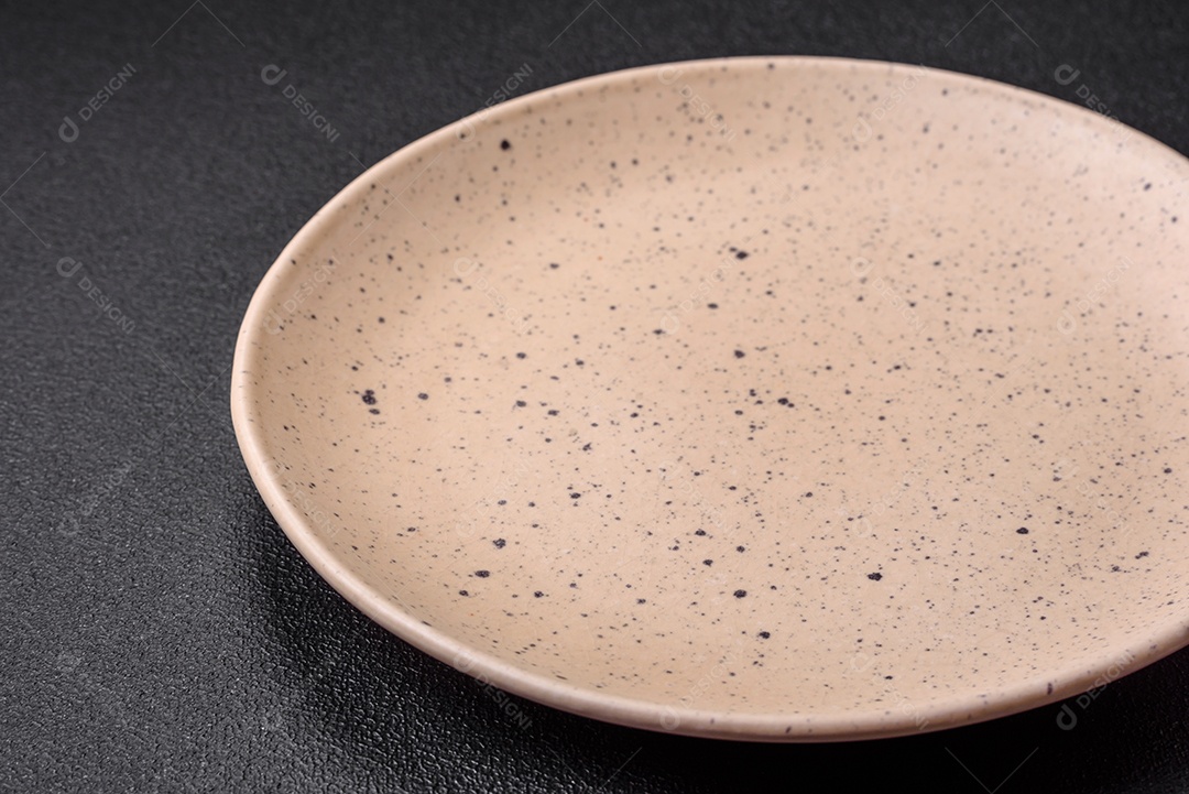 Prato cerâmico vazio em um fundo escuro texturizado. Preparando utensílios de cozinha para um jantar em família