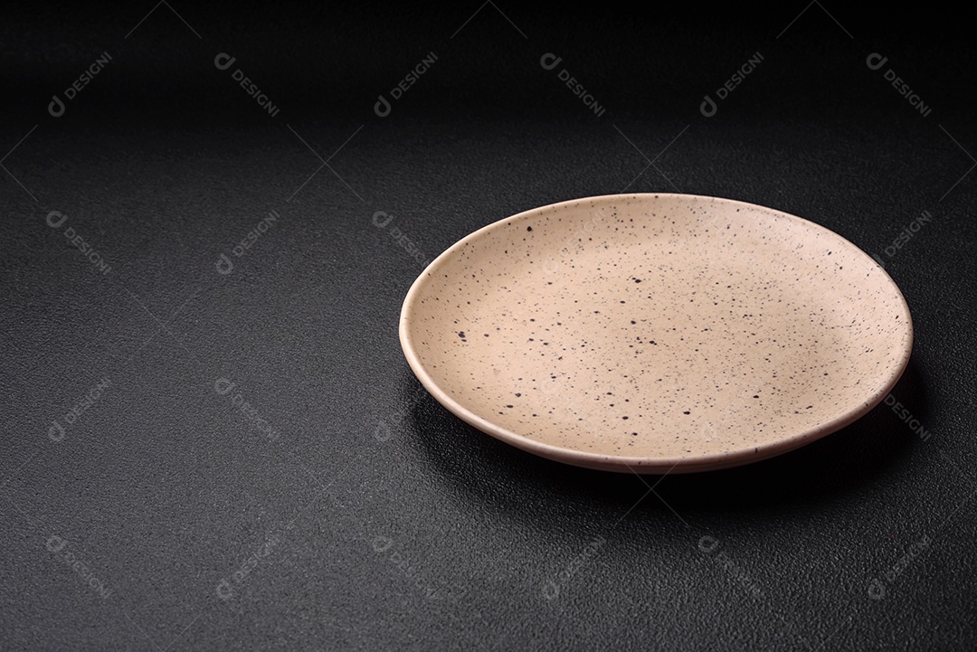 Prato cerâmico vazio em um fundo escuro texturizado. Preparando utensílios de cozinha para um jantar em família