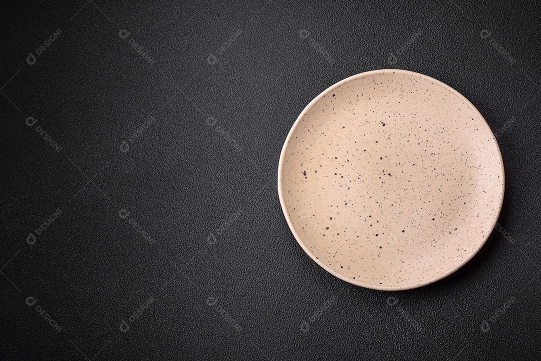 Prato cerâmico vazio em um fundo escuro texturizado. Preparando utensílios de cozinha para um jantar em família