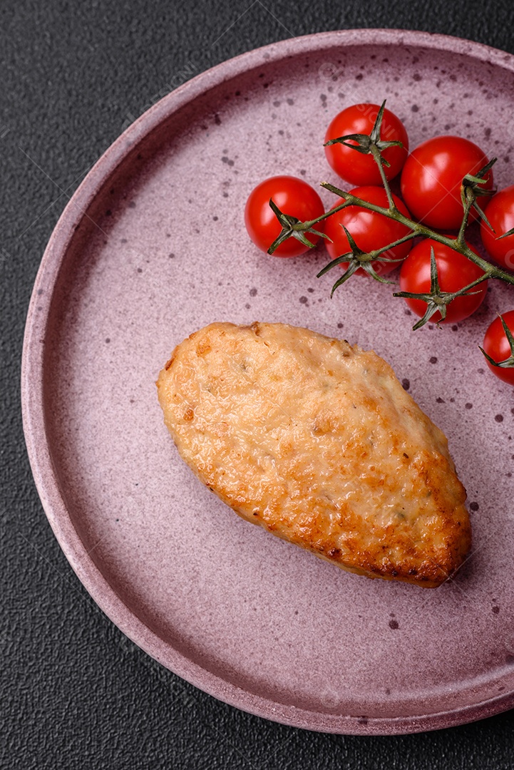 Deliciosas costeletas de frango fresco ou almôndegas com sal, especiarias e ervas sobre um fundo escuro de concreto