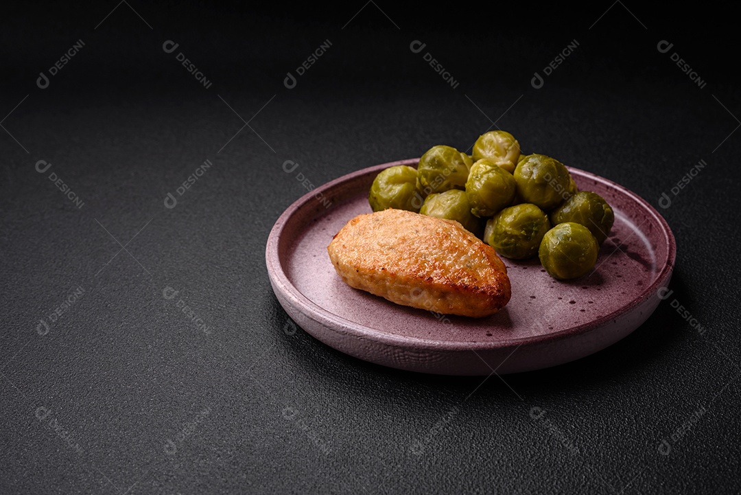 Deliciosas couves de Bruxelas cozidas em um prato de cerâmica sobre um fundo escuro de concreto. Comida vegetariana