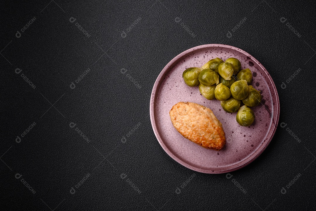 Deliciosas couves de Bruxelas cozidas em um prato de cerâmica sobre um fundo escuro de concreto. Comida vegetariana
