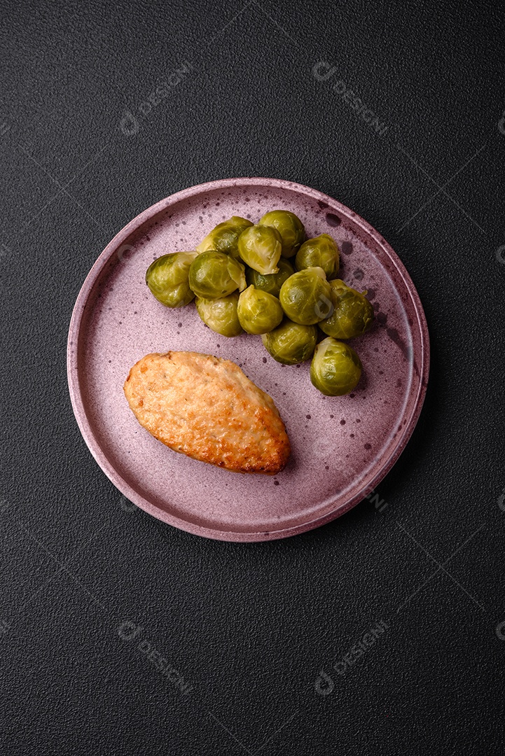 Deliciosas couves de Bruxelas cozidas em um prato de cerâmica sobre um fundo escuro de concreto. Comida vegetariana