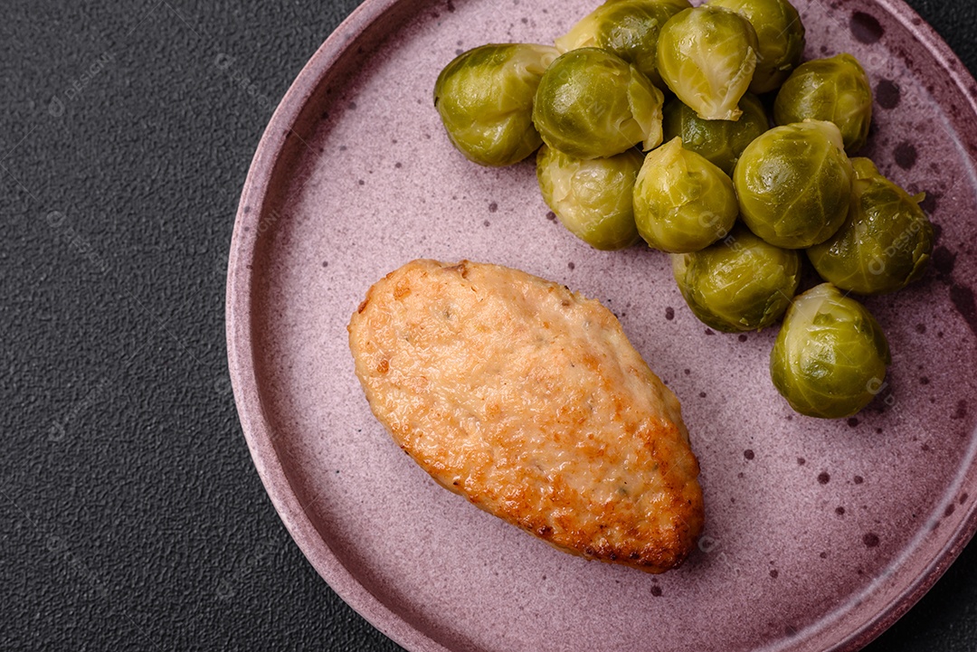 Deliciosas couves de Bruxelas cozidas em um prato de cerâmica sobre um fundo escuro de concreto. Comida vegetariana