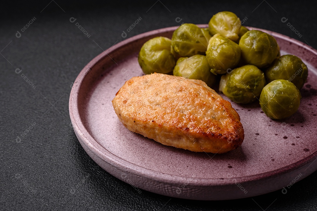 Deliciosas couves de Bruxelas cozidas em um prato de cerâmica sobre um fundo escuro de concreto. Comida vegetariana