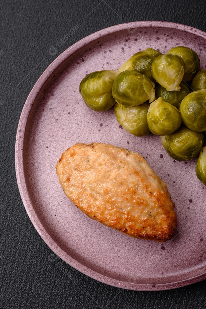 Deliciosas couves de Bruxelas cozidas em um prato de cerâmica sobre um fundo escuro de concreto. Comida vegetariana