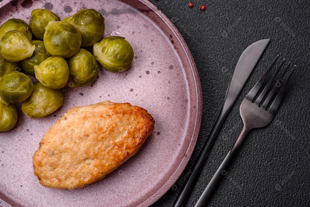 Deliciosas couves de Bruxelas cozidas em um prato de cerâmica sobre um fundo escuro de concreto. Comida vegetariana