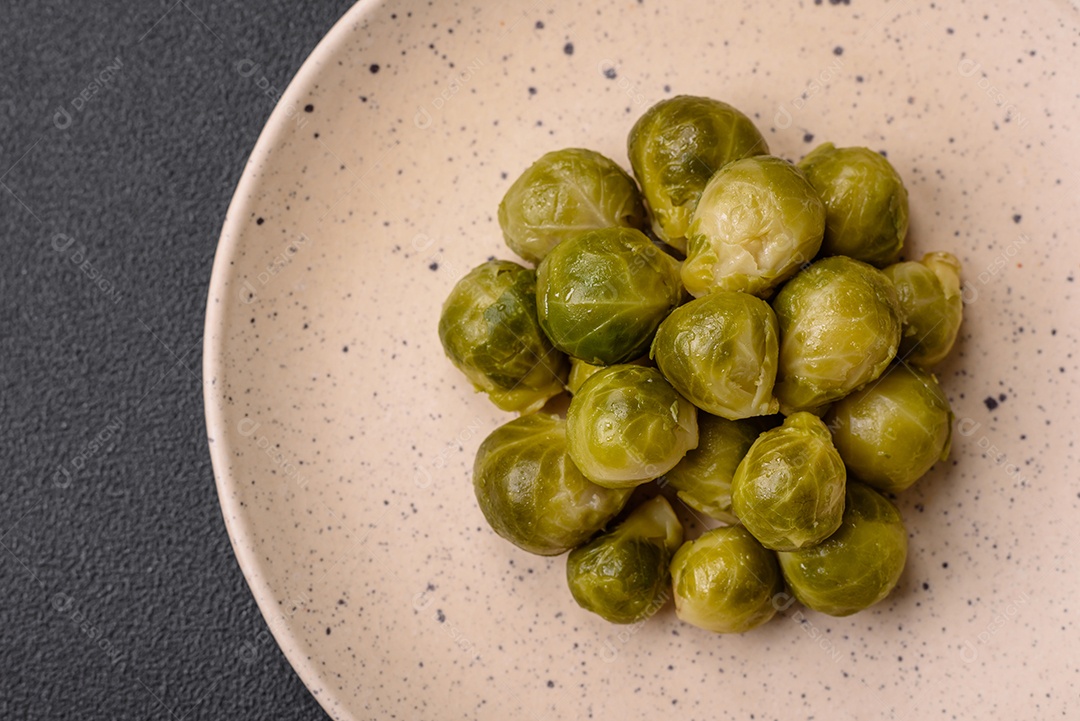 Deliciosas couves de Bruxelas cozidas em um prato de cerâmica sobre um fundo escuro de concreto. Comida vegetariana