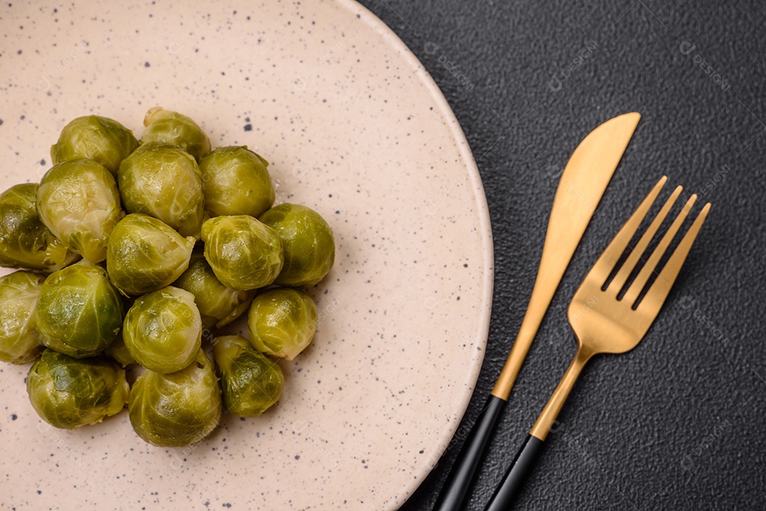Deliciosas couves de Bruxelas cozidas em um prato de cerâmica sobre um fundo escuro de concreto. Comida vegetariana