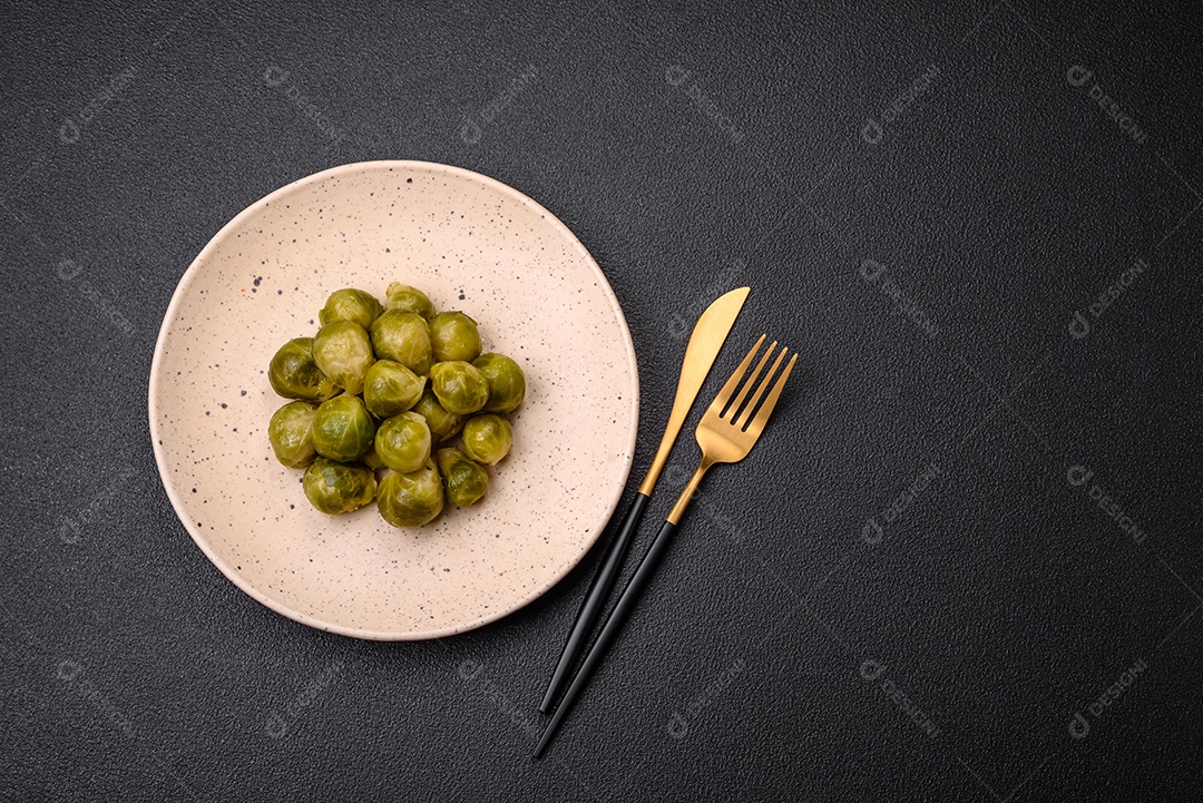 Deliciosas couves de Bruxelas cozidas em um prato de cerâmica sobre um fundo escuro de concreto. Comida vegetariana