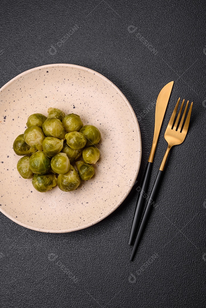 Deliciosas couves de Bruxelas cozidas em um prato de cerâmica sobre um fundo escuro de concreto. Comida vegetariana