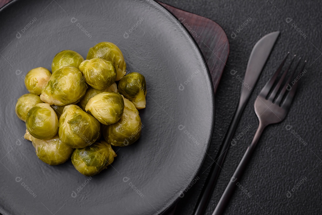 Deliciosas couves de Bruxelas cozidas em um prato de cerâmica sobre um fundo escuro de concreto. Comida vegetariana