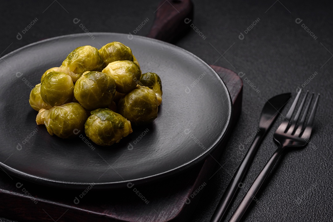 Deliciosas couves de Bruxelas cozidas em um prato de cerâmica sobre um fundo escuro de concreto. Comida vegetariana
