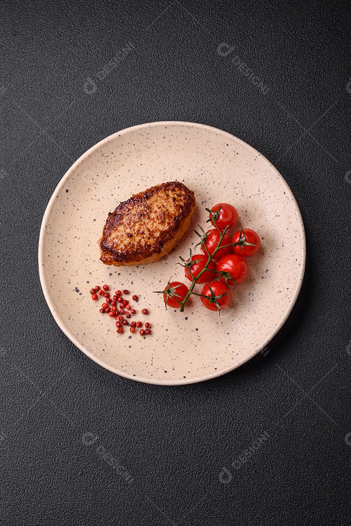 Deliciosa costeleta de soja vegetariana frita fresca com sal, especiarias e ervas com legumes em uma placa de cerâmica sobre um fundo escuro de concreto