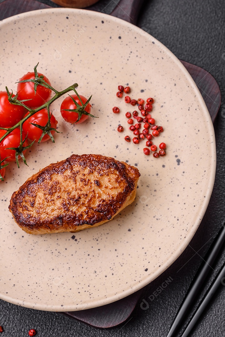 Deliciosa costeleta de soja vegetariana frita fresca com sal, especiarias e ervas com legumes em uma placa de cerâmica sobre um fundo escuro de concreto
