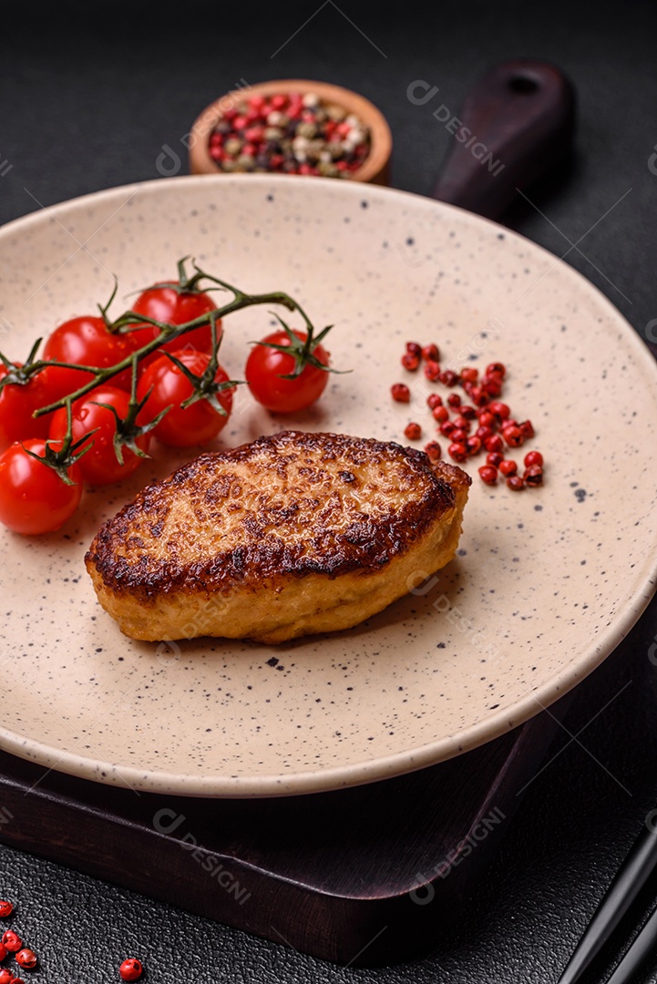 Deliciosa costeleta de soja vegetariana frita fresca com sal, especiarias e ervas com legumes em uma placa de cerâmica sobre um fundo escuro de concreto