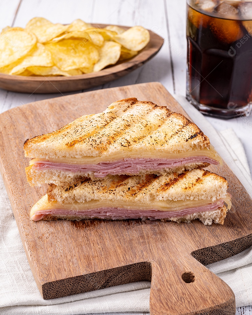 Sanduíche de queijo e presunto com batata frita e refrigerante.