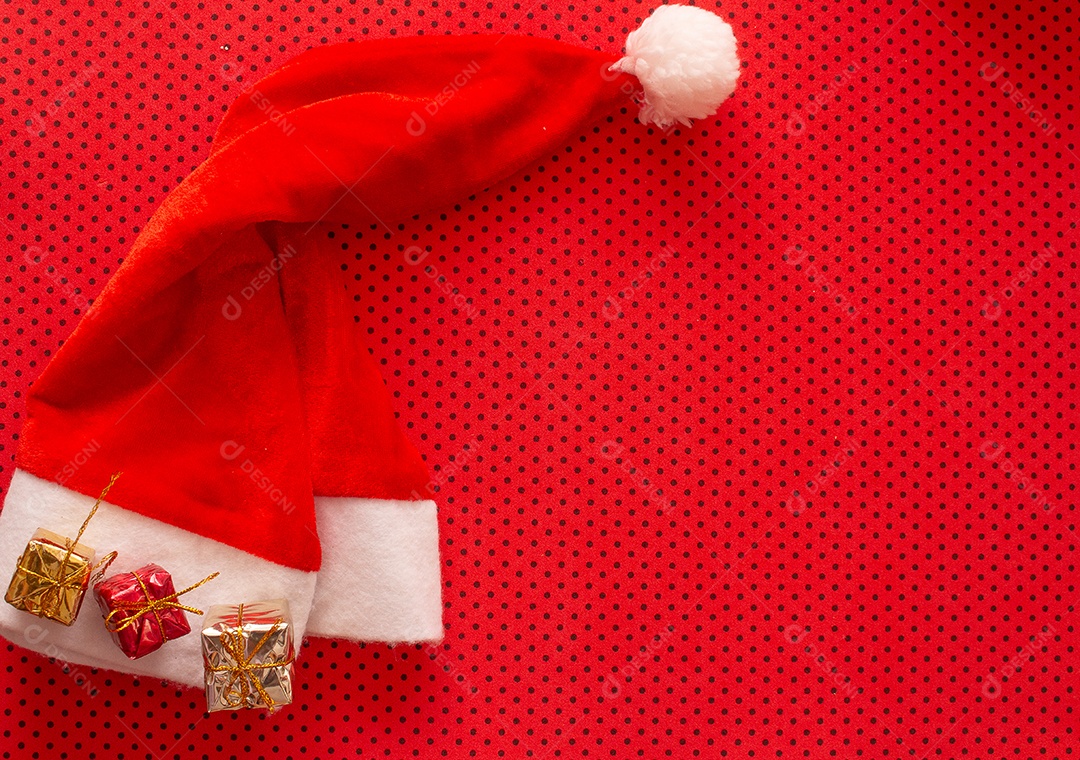 Gorro do papai noel vermelho e minis presentes sobre fundo de pintinhas