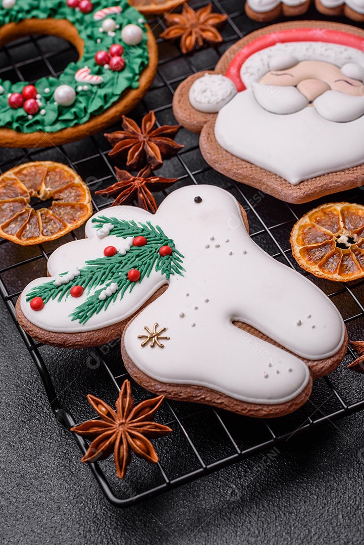 Biscoitos de gengibre frescos e deliciosos de Natal ou ano novo com padrão temático de cor brilhante em fundo escuro de concreto